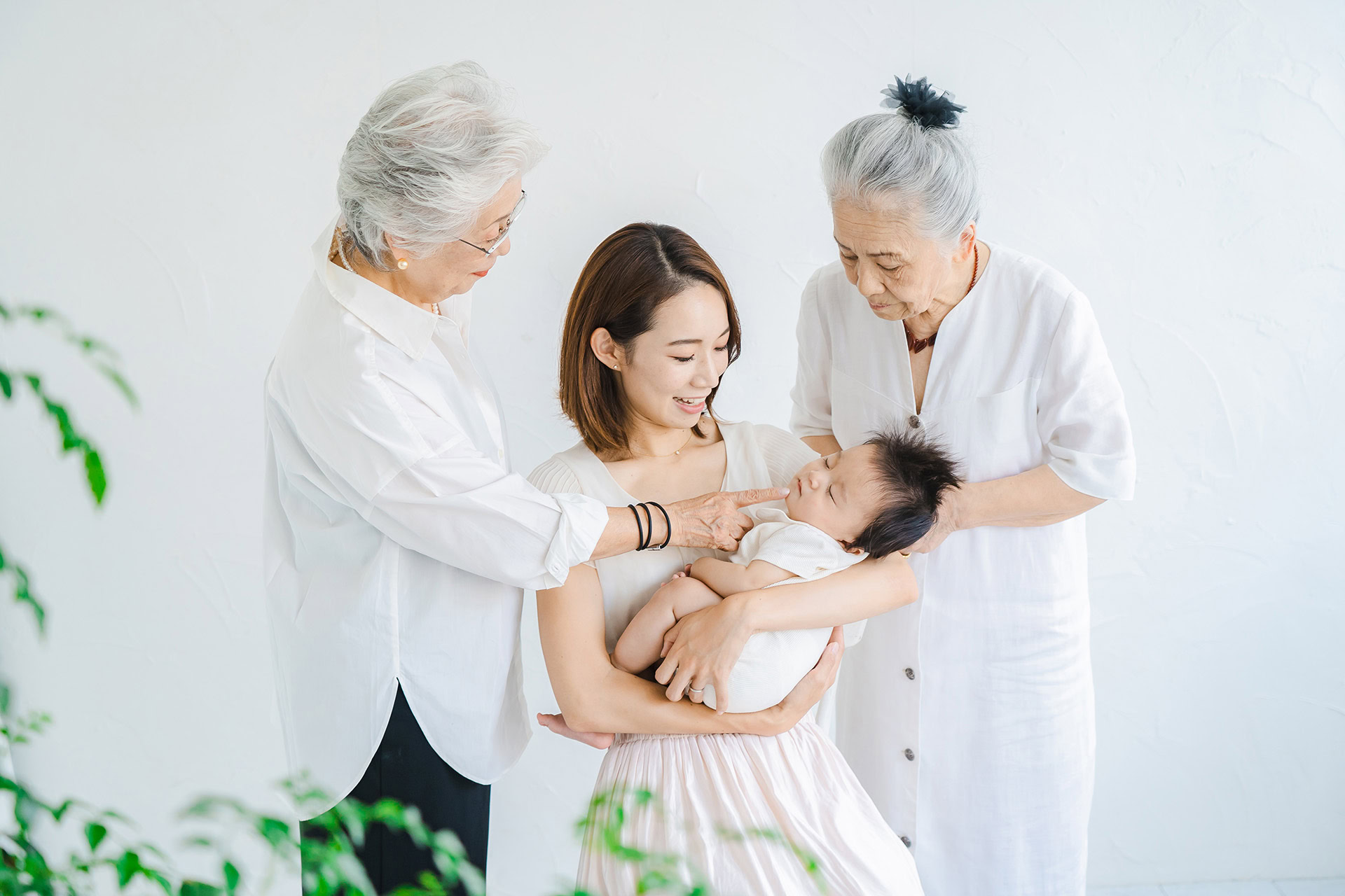 asian mom holding baby two senior women