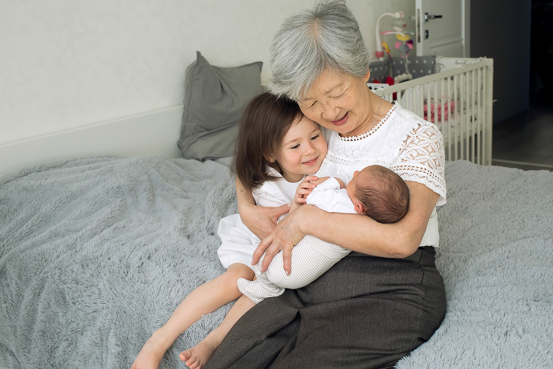 great grandmother hugs two great granddaughters