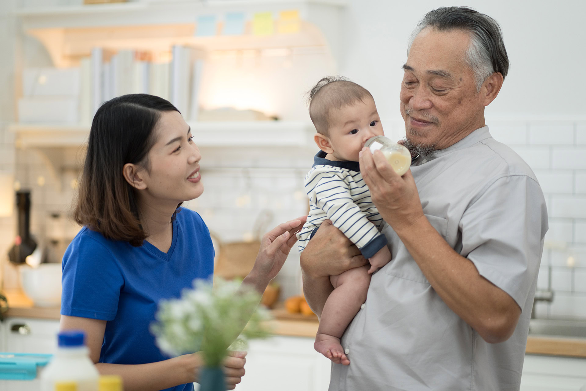 mom watching grandpa feeding baby